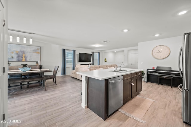 kitchen featuring sink, dark brown cabinetry, a center island with sink, and stainless steel appliances