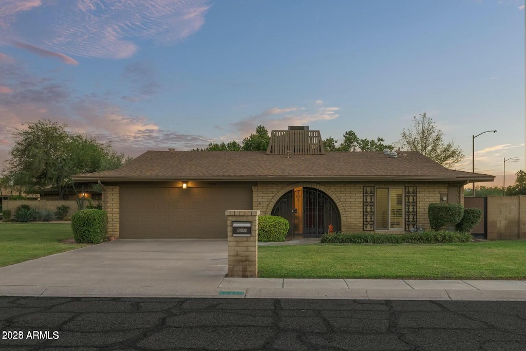 view of front facade with a garage, a front yard, brick siding, and driveway