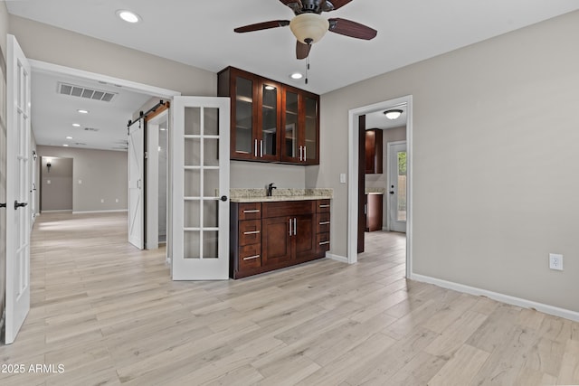 9917 W Cameo Dr, Sun City, AZ 85351 - bar featuring a barn door, ceiling fan, light wood-type flooring, baseboards, and recessed lighting