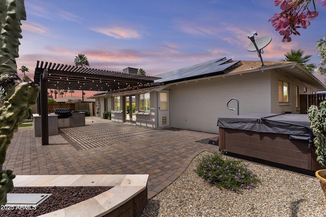 9917 W Cameo Dr, Sun City, AZ 85351 - back of property at dusk featuring a hot tub, solar panels, a patio area, a pergola, and fence