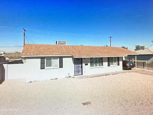 single story home featuring a shingled roof, fence, and driveway