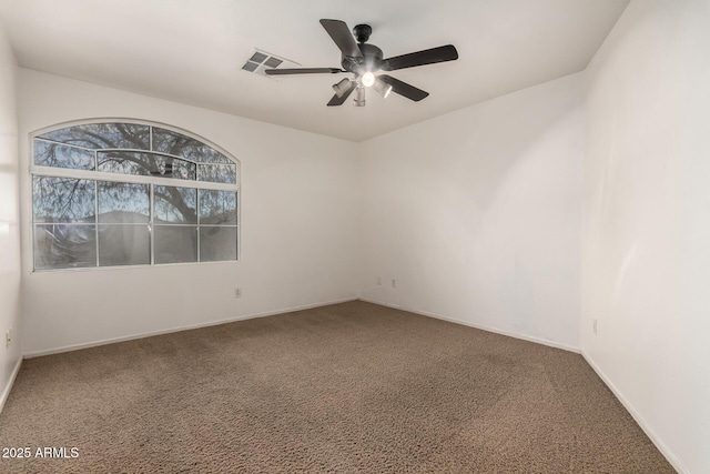 carpeted spare room with visible vents, a ceiling fan, and baseboards