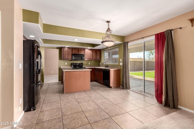 kitchen featuring a center island, light countertops, hanging light fixtures, a sink, and black appliances