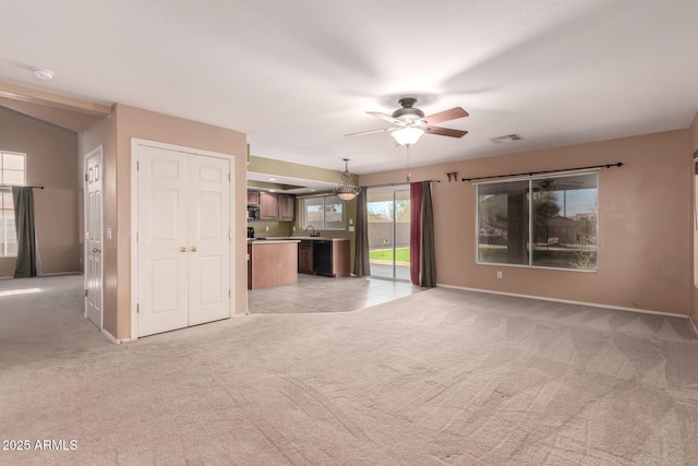 unfurnished living room featuring light carpet, a sink, visible vents, baseboards, and a ceiling fan