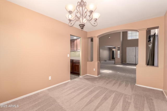 spare room featuring light carpet, ornate columns, baseboards, and arched walkways