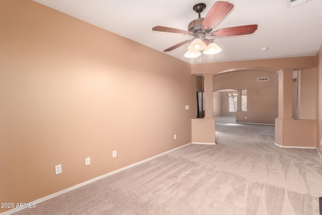 spare room with arched walkways, baseboards, light colored carpet, ceiling fan, and ornate columns