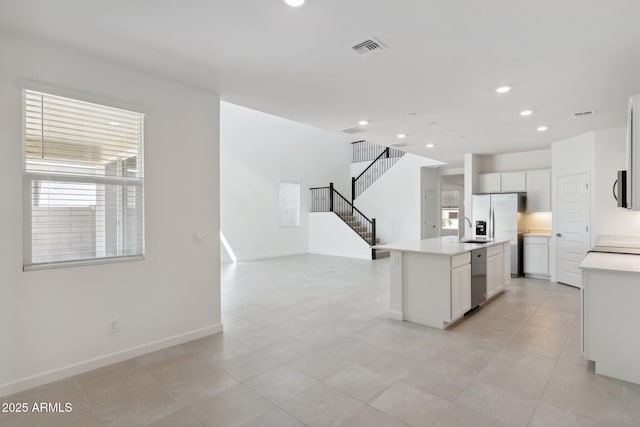 kitchen featuring sink, stainless steel appliances, white cabinets, and a center island with sink