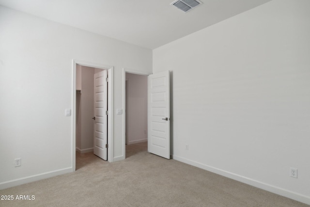 unfurnished bedroom featuring a walk in closet and light colored carpet