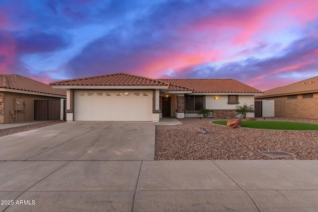 view of front of home featuring a tile roof, stucco siding, concrete driveway, a garage, and stone siding