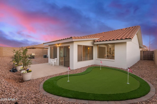 back of property featuring a tile roof, a patio area, brick siding, and a fenced backyard