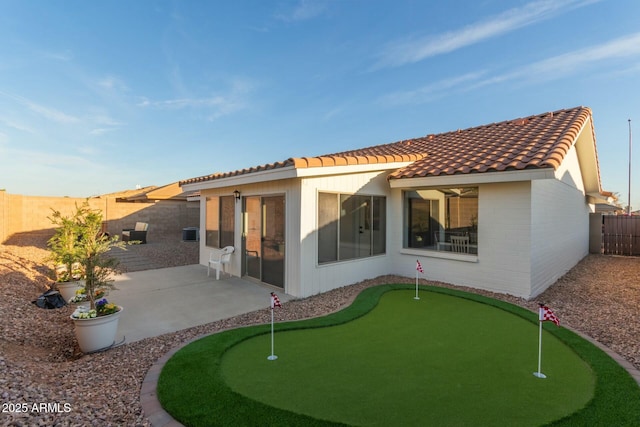 rear view of property with a patio area, a tile roof, a fenced backyard, and brick siding