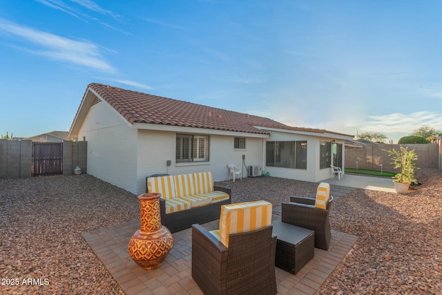 back of property with a tile roof, an outdoor living space, a fenced backyard, and a patio