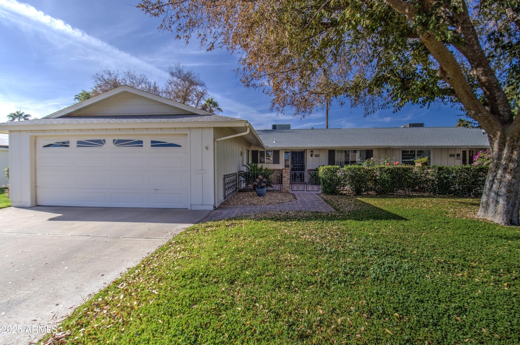 ranch-style home with a garage and a front lawn