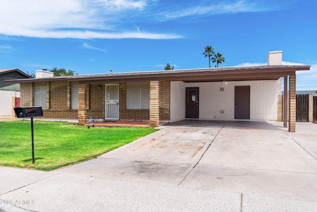 ranch-style home featuring concrete driveway, a chimney, a front yard, and a carport