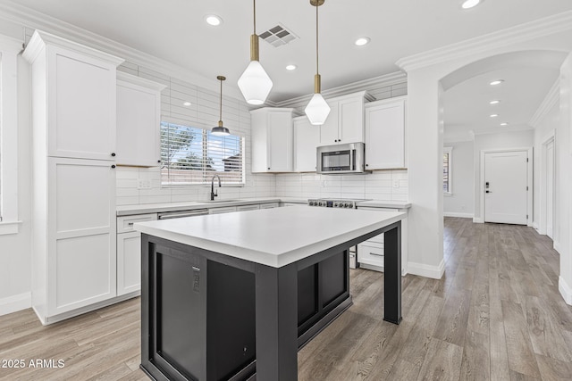 18998 E Lark Dr, Queen Creek, AZ 85142 - kitchen featuring stainless steel microwave, arched walkways, a sink, white cabinets, and light countertops