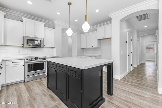 18998 E Lark Dr, Queen Creek, AZ 85142 - kitchen with stainless steel appliances, arched walkways, white cabinets, dark cabinets, and light countertops