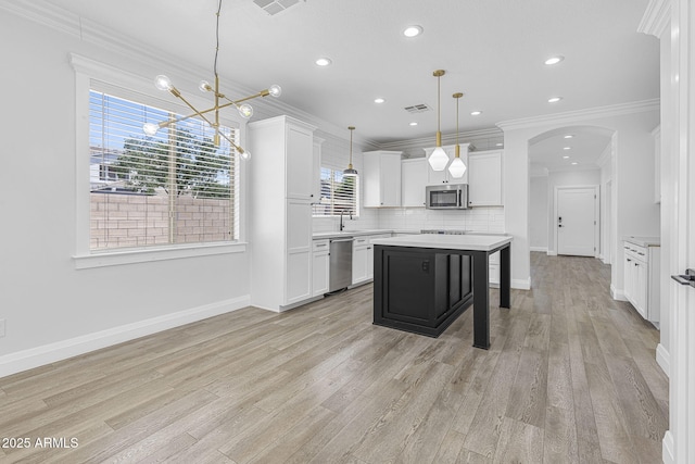 18998 E Lark Dr, Queen Creek, AZ 85142 - kitchen with stainless steel appliances, light countertops, ornamental molding, light wood-type flooring, and arched walkways