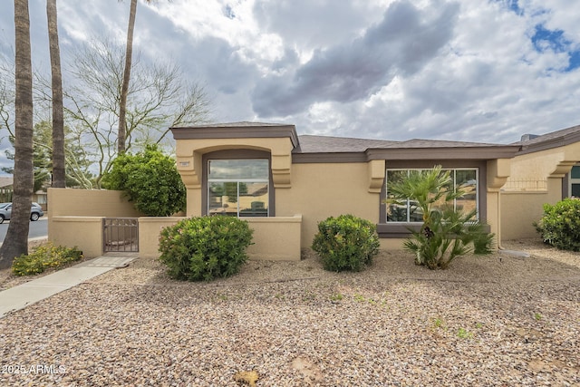 view of front of house with stucco siding, a fenced front yard, and a gate