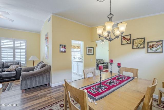 dining area featuring visible vents, wood finished floors, crown molding, and ceiling fan with notable chandelier