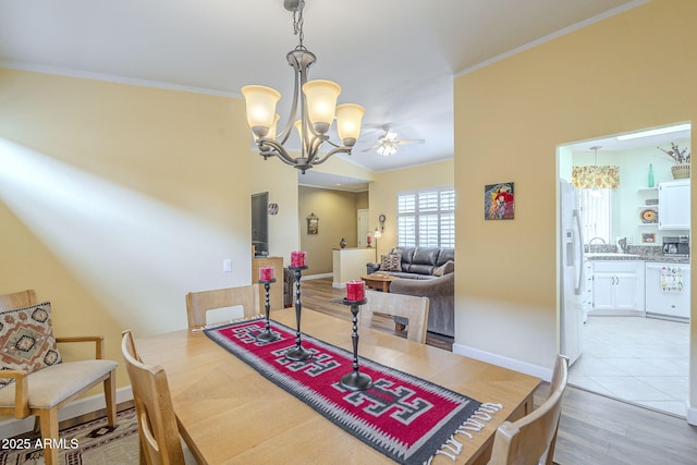 dining area featuring baseboards, a chandelier, crown molding, and light wood finished floors