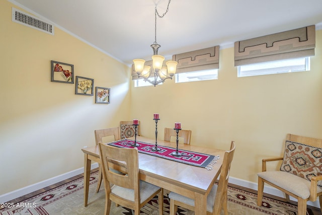 dining space with baseboards, wood finished floors, visible vents, and a chandelier