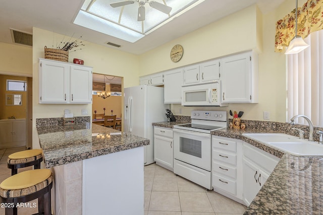 kitchen with visible vents, a breakfast bar, a skylight, white appliances, and a sink