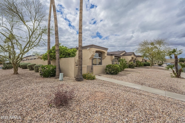 view of side of property featuring a fenced front yard and stucco siding