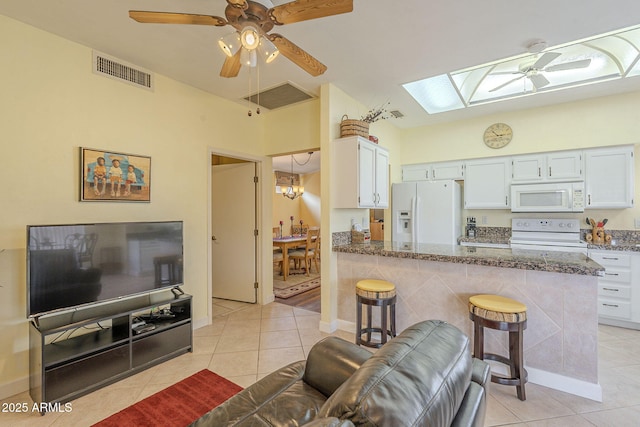 living room with a skylight, light tile patterned floors, visible vents, and ceiling fan