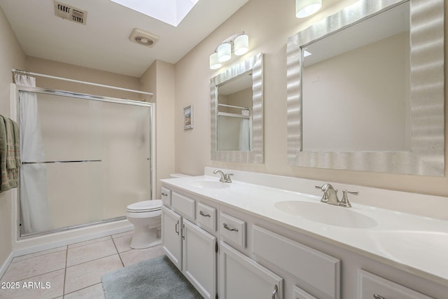 bathroom featuring tile patterned flooring, a stall shower, a skylight, and a sink