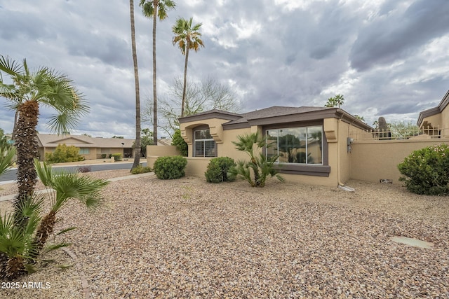 back of house featuring stucco siding and fence