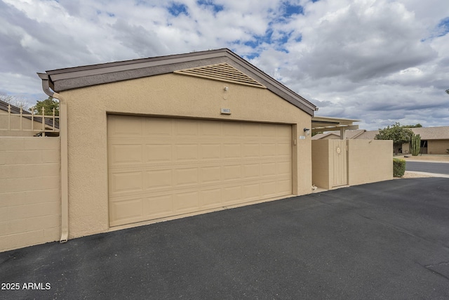 garage featuring driveway and fence