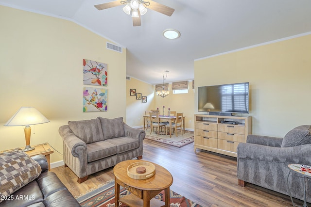 living area featuring visible vents, ornamental molding, ceiling fan with notable chandelier, wood finished floors, and lofted ceiling