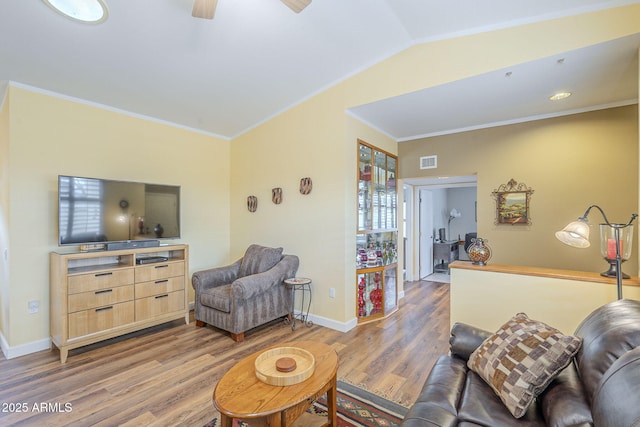 living room featuring visible vents, baseboards, lofted ceiling, ornamental molding, and wood finished floors