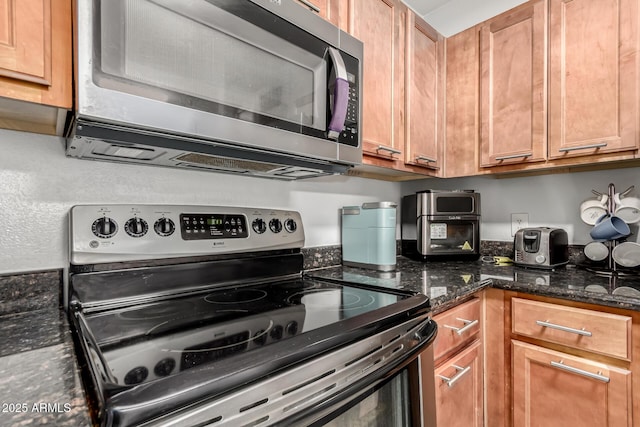 kitchen featuring stainless steel appliances and dark stone counters