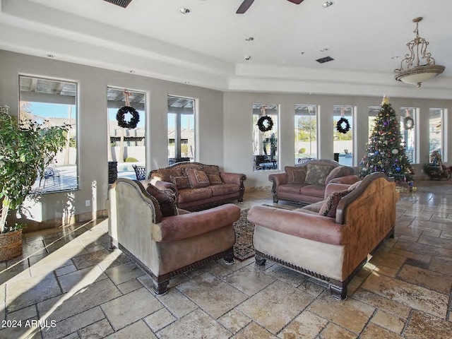 living room with ceiling fan, a raised ceiling, and a wealth of natural light