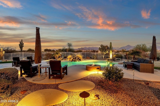 pool at dusk featuring a mountain view, a patio area, and an outdoor fire pit