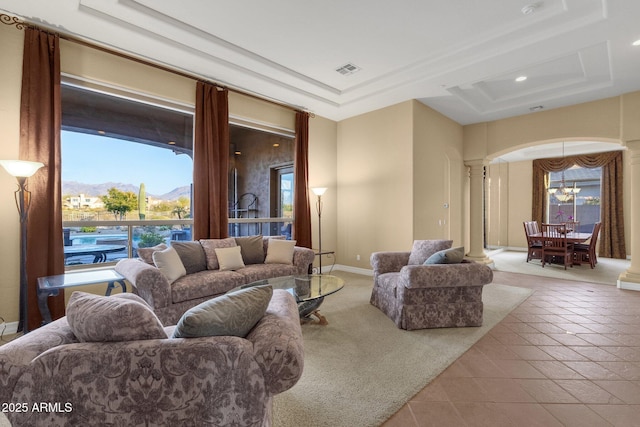 tiled living room with a mountain view, a tray ceiling, a notable chandelier, and ornate columns