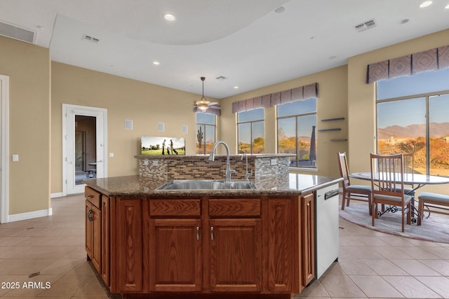 kitchen featuring dishwasher, an island with sink, sink, backsplash, and light tile patterned floors