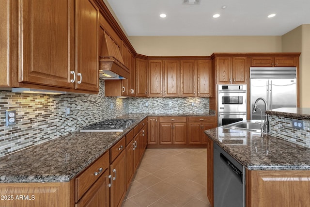 kitchen with stainless steel appliances, sink, dark stone countertops, and decorative backsplash