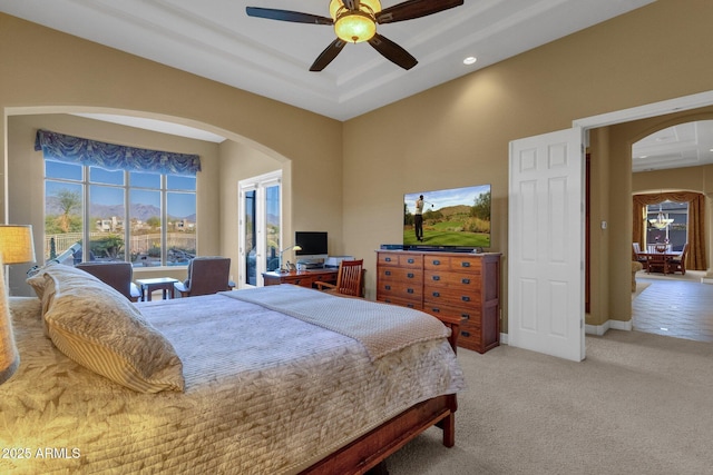 bedroom featuring ceiling fan, a tray ceiling, and light carpet