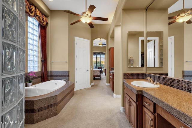 bathroom with backsplash, vanity, a relaxing tiled tub, ceiling fan, and a high ceiling