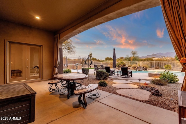 patio terrace at dusk with french doors and a fenced in pool