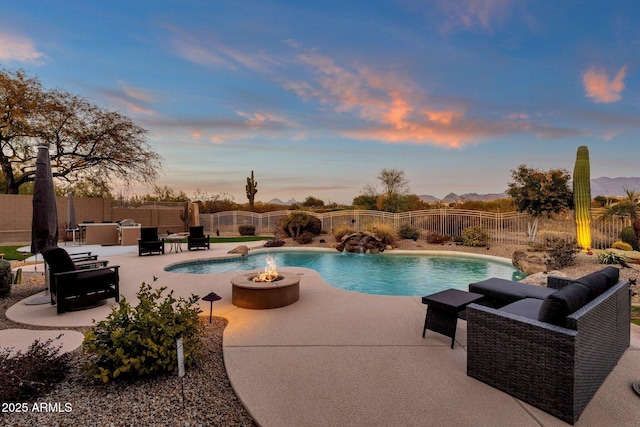 pool at dusk with a patio, an outdoor living space with a fire pit, and pool water feature