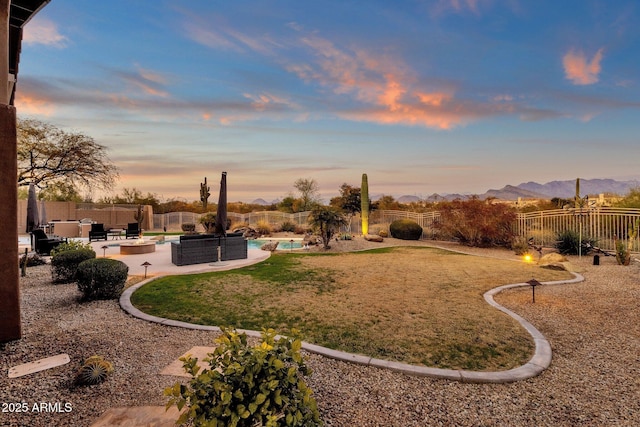 yard at dusk featuring a mountain view, a swimming pool, a patio, and an outdoor fire pit