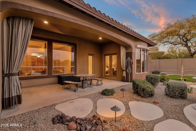 back house at dusk featuring a patio area