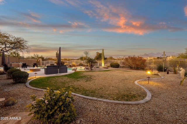 yard at dusk featuring a mountain view, a patio area, and an outdoor living space with a fire pit