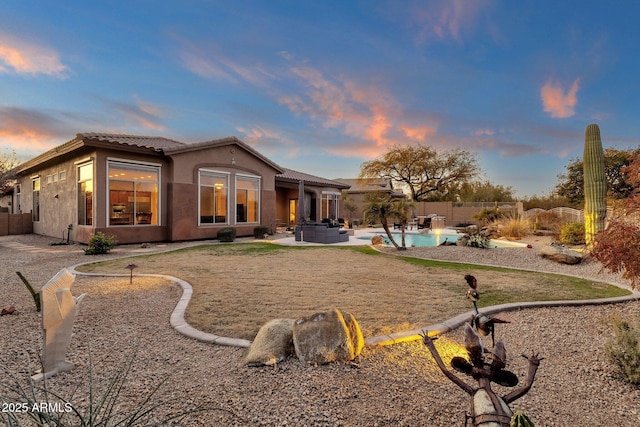 back house at dusk with a fenced in pool and a patio area