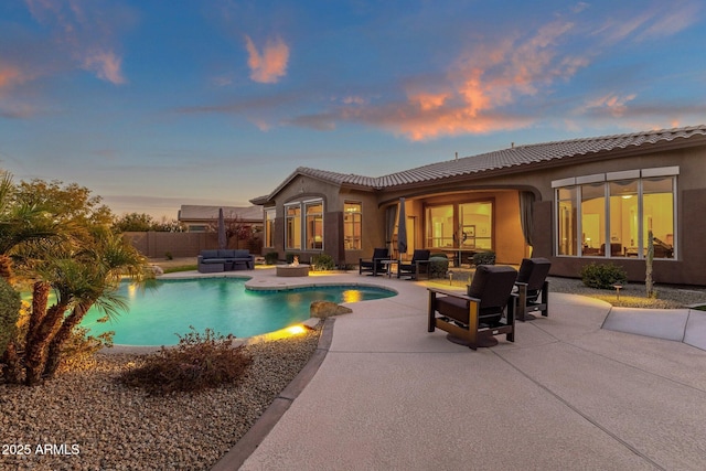 pool at dusk with an outdoor hangout area and a patio area