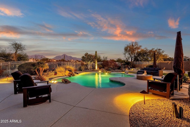 pool at dusk with a mountain view, a patio, and an outdoor living space with a fire pit