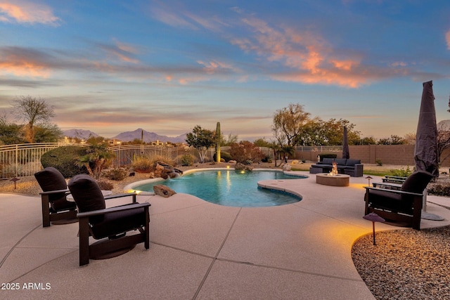 pool at dusk featuring a mountain view, an outdoor hangout area, pool water feature, and a patio area